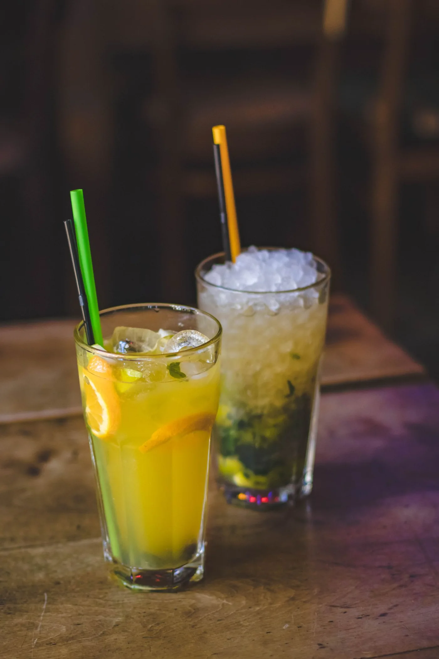Zwei sommerliche Cocktails mit Zitrusfrüchten und Minze auf einem Holztisch