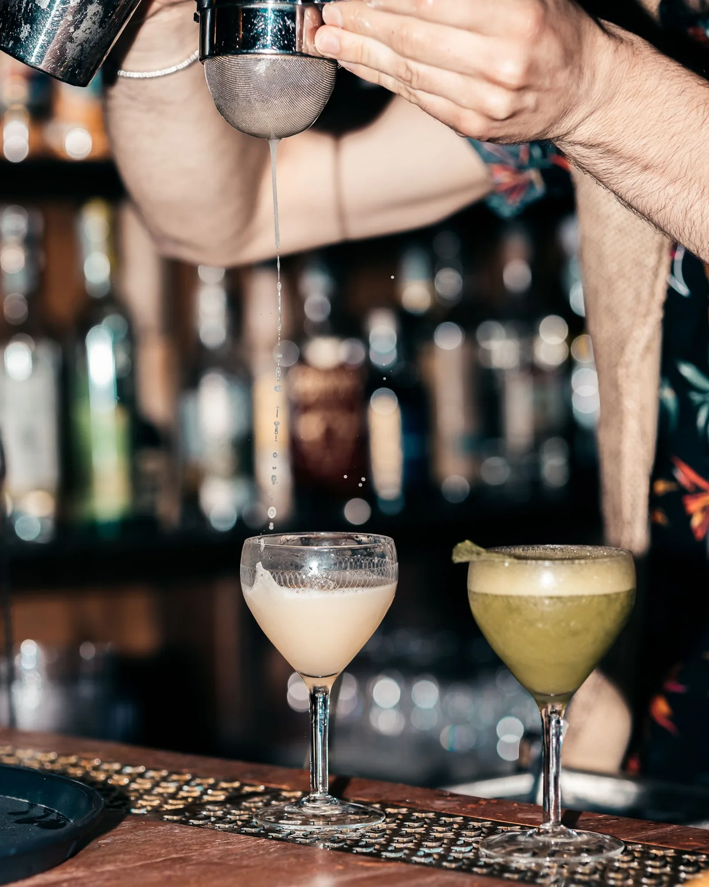 Hände bei der Zubereitung zweier Cocktails mit einem Shaker